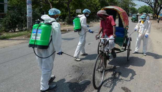Volunteers spray disinfectant on a rickshaw along a road during a government-imposed shut-down as a preventive measure against the Covid-19 coronavirus, in Dhaka yesterday.