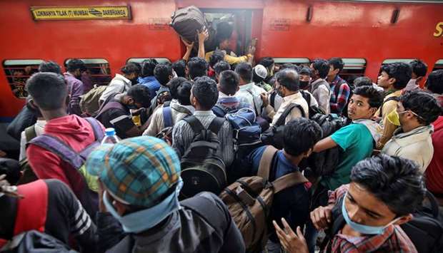 Migrant workers and their families board an overcrowded passenger train, after government imposed restrictions on public gatherings in attempts to prevent spread of coronavirus disease, in Mumbai. For many poor people in India, where the economy was locked down this week, the economic crisis will be immediate.
