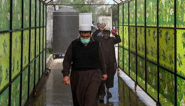 Residents wearing face masks walk through a disinfecting tunnel at a vegetable and fruit market during a government-imposed nationwide lockdown against the Covid-19 coronavirus, in Islamabad yesterday.