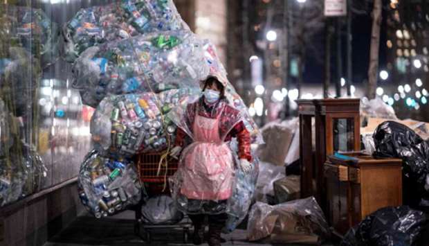A woman pulls a cart loaded with bags of recyclables through the streets of lower Manhattan in New York City.