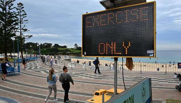 People walk past a sign reading ,exercise only, at Coogee Beach in Sydney