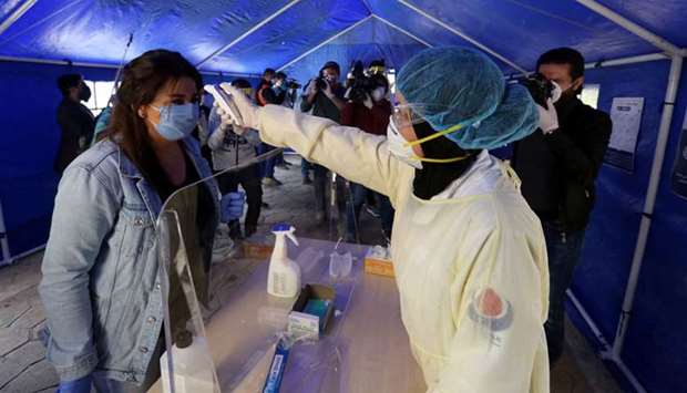 A medic from Hezbollahu2019s Islamic health unit checks the temperature of a woman, inside a tent facility to test for coronavirus disease (Covid-19), during a media tour organised by officials in Beirutu2019s southern suburb.