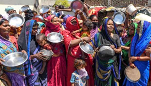 Migrant labourers and families from Bihar and Uttar Pradesh hold kitchen utensils as they protest against the government for the lack of food at a slum area in Amritsar yesterday.