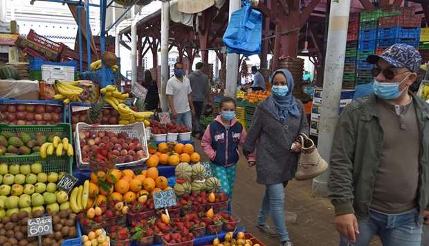 Tunisian, wearing protective masks, walk past stalls in a central market in the capital Tunis yesterday, during the first day of the holy month of Ramadan, after authorities partially eased the lockdown measures.
