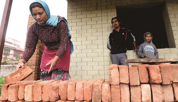Husband and wife Rabindra (centre) and Anjana Tajale (left) work on the construction of their new two-room hut during a interview with AFP in Bhaktapur on the outskirts of Kathmandu.