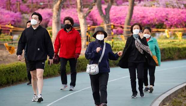 People wearing masks walk at a park in Seoul, South Korea, yesterday.