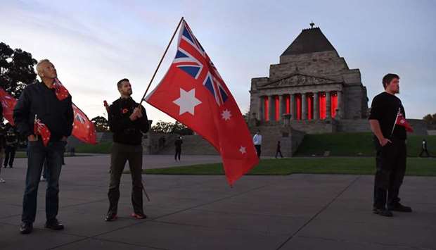 People hold flags as they pay their respects during the Anzac Day dawn service at the Shrine of Remembrance in Melbourne yesterday.