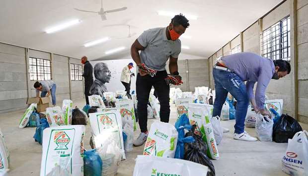 South African Rugby national team captain Siya Kolisi (centre) and members of the Nelson Mandela Foundation packs protective face masks inside food parcels to be handed to child-headed families in Zandspruit informal settlement, north of Johannesburg.