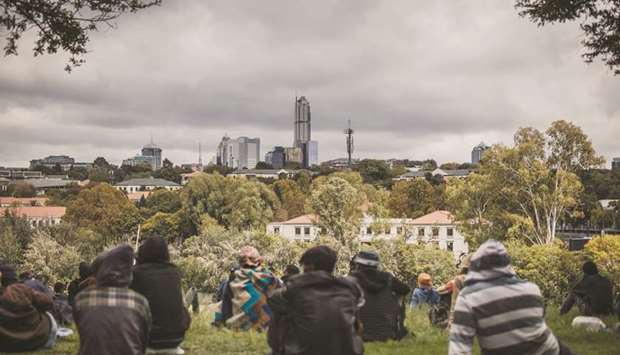 The skyline of the district of Sandton is seen as a group of homeless persons gather in  Innesfree Park in Johannesburg on April 9.