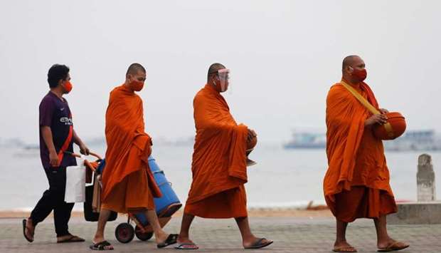 Buddhist monks wearing protective face masks walk to collect alms at an almost empty beach, which is usually crowed with tourists, following the coronavirus disease outbreak in Pattaya, Thailand
