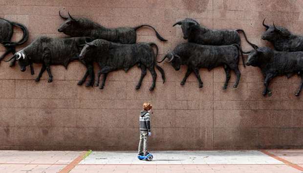 A child rides a hoverboard past bull sculptures outside Las Ventas bullring in Madrid.