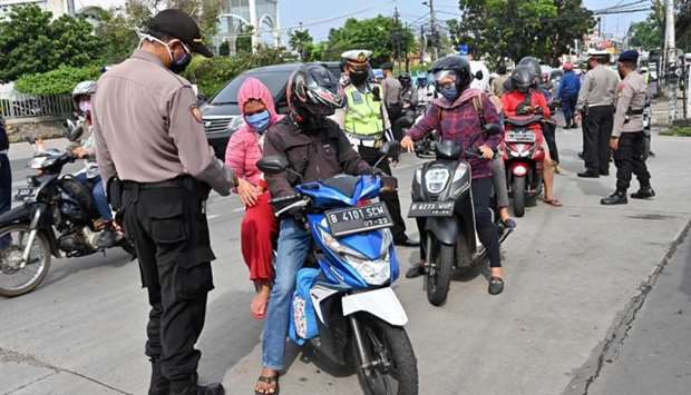 Indonesian policemen check the IDs of motorists at the border between Jakarta and Tangerang after the government imposed a large-scale social restrictions to curb the spread of the Covid-19 in Jakarta