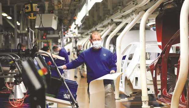 An automobile assembly line worker wears a protective face mask as Volkswagen (VW) restarted production at their headquarter factory in Wolfsburg, Germany, yesterday. Volkswagen group is resuming production at factories in Portugal, Spain, Russia, South Africa, and the Czech Republic as well this week.