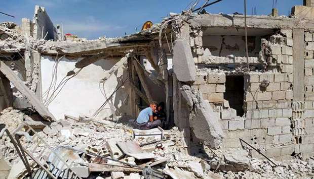 A handout picture released by the official Syrian Arab News Agency (SANA) yesterday shows two youth sitting amid the debris of a building after an Israeli air strike, south of the Syrian capital Damascus.
