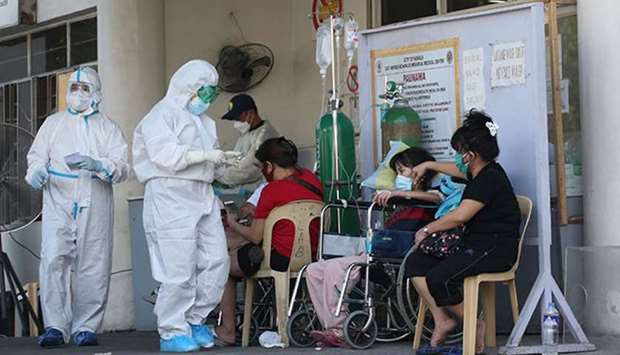 Nurses wearing Personal Protective Equipment (PPE) attend to patients on the driveway of Gat Andres Bonifacio Memorial Hospital serving as triage area due to the overwhelming numbers.
