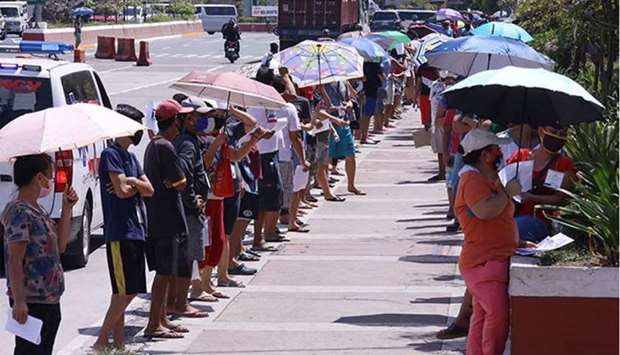 Beneficiaries of the governmentu2019s Social Amelioration Programme endure the heat as they line up outside the Batasan High School in Quezon City where the cash assistance for poor households was distributed.