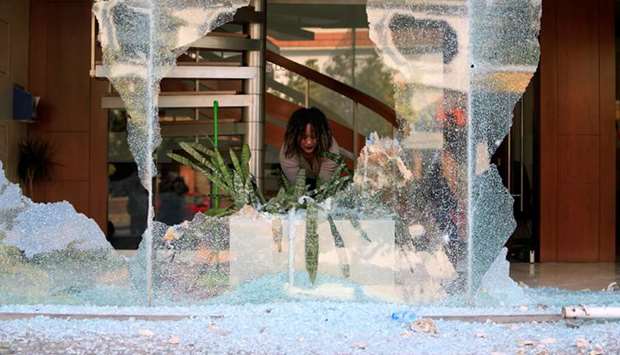 A worker cleans up broken glass from a bank facade after overnight protests against growing economic hardship in Sidon, Lebanon, yesterday.
