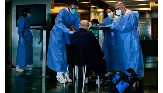 Healthcare workers attend to a Covid-19 patient upon his arrival at the Hotel Melia Barcelona Sarria in Barcelona, as the hotel was transformed into a medical structure to treat the least serious coronavirus cases.