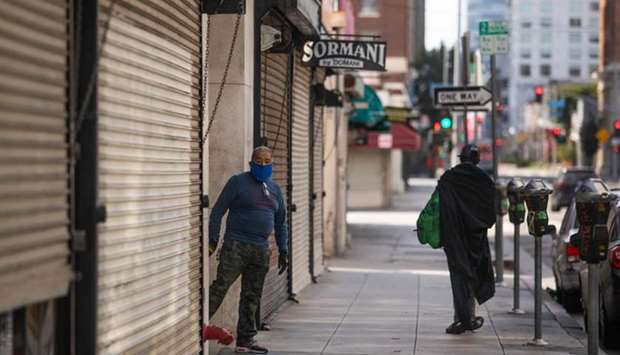 A private security guard wearing a face mask stands next to closed stores in the Fashion District in Downtown Los Angeles, California