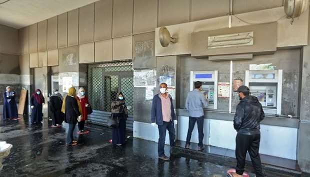 Libyans wearing protective face masks queue inside a bank in the centre of the capital Tripoli on April 1 amidst the novel coronavirus pandemic crisis