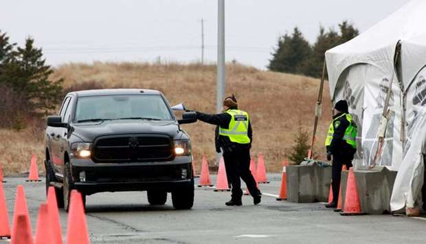 A Nova Scotia conservation officer passes a paper to a person crossing into the province from New Brunswick in its effort to prevent the spread of the coronavirus disease (Covid-19) at the Fort Lawrence, Canada