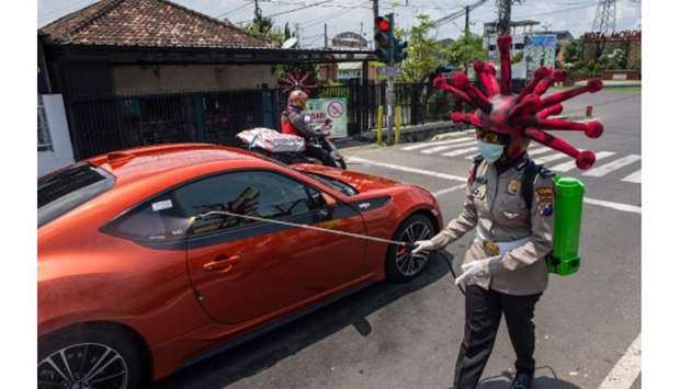 A worker wearing Covid-19 coronavirus-shape-helmet disinfects a vehicle in Mojokerto, East Java, yesterday, as a preventive measure against the  coronavirus spread.