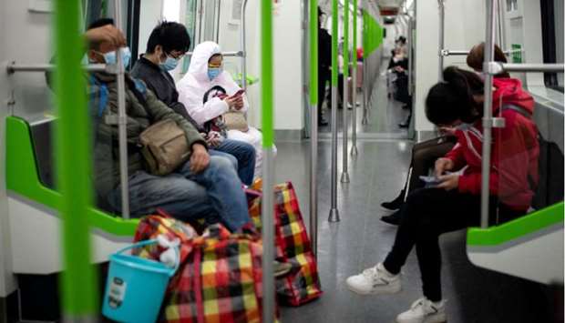 Passengers wearing face masks uses their mobile phones on a train in Wuhan.