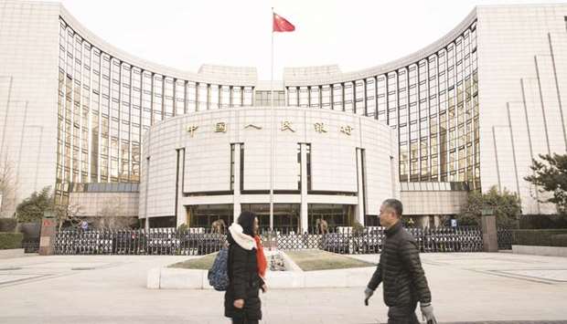 Pedestrians walk past the Peopleu2019s Bank of China headquarters in Beijing. The Chinese central bank said on its website it will cut the reserve requirement ratio for those banks by 100 basis points in two equal steps, the first effective as of April 15 and the second as of May 15.
