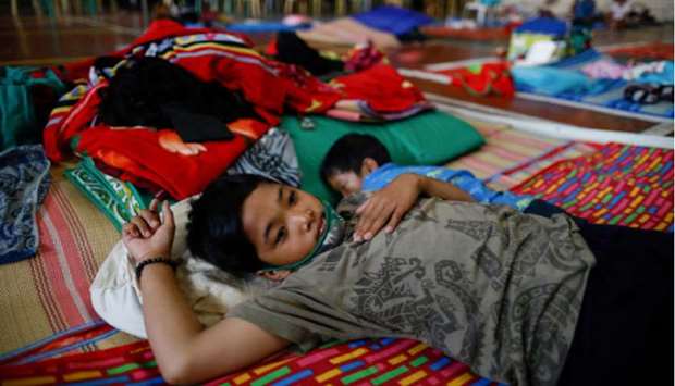 A boy rests beside his brother in a schoolu2019s gymnasium which turned into a shelter for the homeless following the enforcement of a community quarantine in the Philippine main island to contain the coronavirus disease (Covid-19), in Manila.