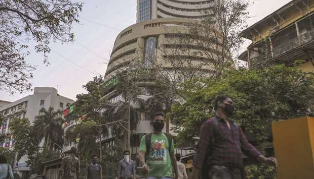 Pedestrians wearing protective masks walk past the Bombay Stock Exchange building in Mumbai. The Sensex slid 2.4% to close at 27,590.95 points yesterday and capped seven straight weeks of declines, last seen in 2008.