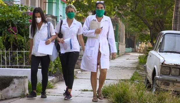 Cuban doctor Liz Caballero (right), from El Vedado polyclinic in Havana, walks with two students as they go door by door looking for possible cases of the novel coronavirus.