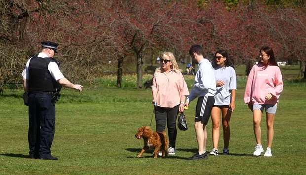An officer speaks with people in Greenwich Park as more cases of the coronavirus disease Covid-19 are reported in the UK.