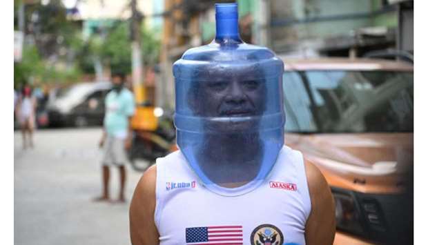 A resident using an improvised face shield made from a plastic water container, to protect him from the Covid-19 coronavirus pandemic, walks in his neighbourhood in Manila, yesterday, after the government imposed enhanced quarantine measures in the city.
