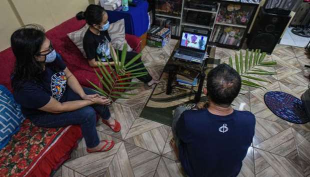 Devotees in an urban community on the outskirts of Manila attend a mass via online live streaming of Palm Sunday, yesterday.