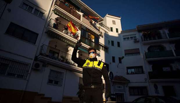A police officer waves as people applaud to thank healthcare workers dealing with the  coronavirus, in Ronda, Spain.