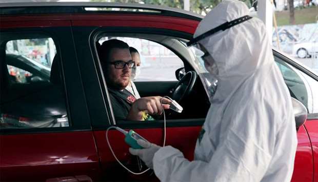 A nurse measures the oxygen level of the blood of a man during drive-thru triage to identify people with coronavirus disease (COVID-19) symptoms in Guarulhos