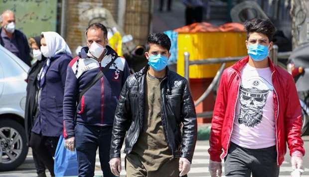 Iranians wear protective face masks against the novel coronavirus as they walk on a street in the capital Tehran, yesterday.