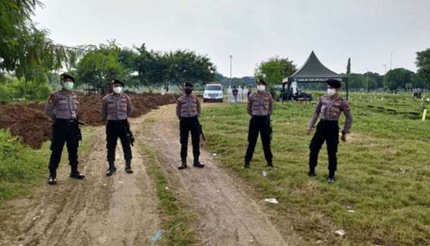 Policemen wearing face masks at a cemetery in Jakarta yesterday, as they guard workers and family members during funerals for victims of the Covid-19 coronavirus.