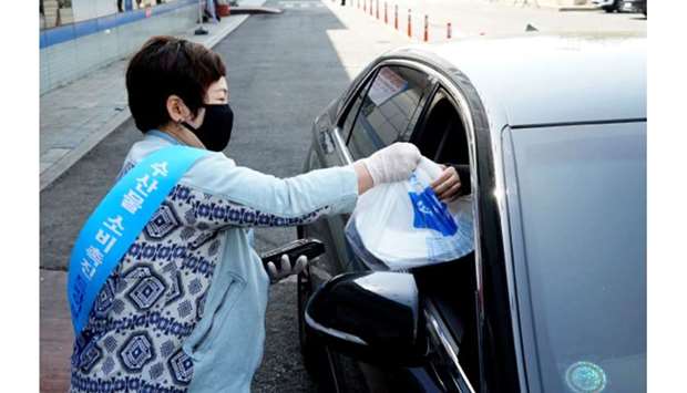 A shopkeeper delivers food at a drive-thru sashimi corner while maintaining social distancing amid the coronavirus outbreak in Seoul, South Korea.