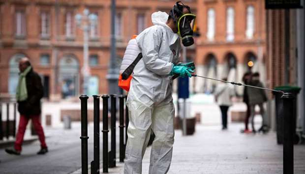 A municipal worker wearing protective gear sprays disinfectants in the street of Toulouse, southern France.