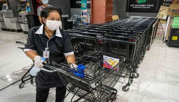 An employee disinfects carts at a supermarket in a shopping mall, closed to combat the spread of the Covid-19 novel coronavirus, in Bangkok yesterday.