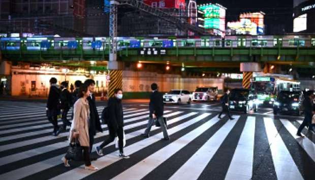 People cross a street in Tokyou2019s Shinjuku district yesterday.
