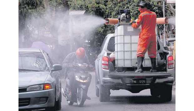 A worker manning a disinfectant truck sprays vehicles in Barangay Pasong Tamo in Quezon City as the government reported 104 new coronavirus cases.