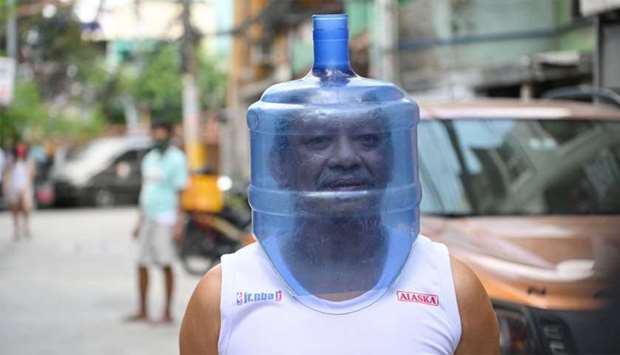 A resident using an improvised face shield made from a plastic water tank to protect him from the COVID-19 coronavirus pandemic walks in his neighbourhood in Manila