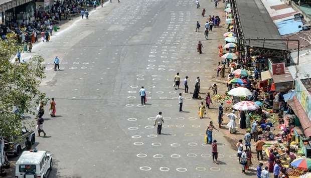 People walk in an area with circles marked on the floor for social distancing as they buy groceries at a temporary market set up at a bus stand in Chennai yesterday.