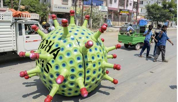 People take photos as inventor Sudhakar Yadav (inside) leads his coronavirus-themed made car on a road for an awareness campaign during a government-imposed nationwide lockdown as a preventive measure against the Covid-19 coronavirus, in Hyderabad