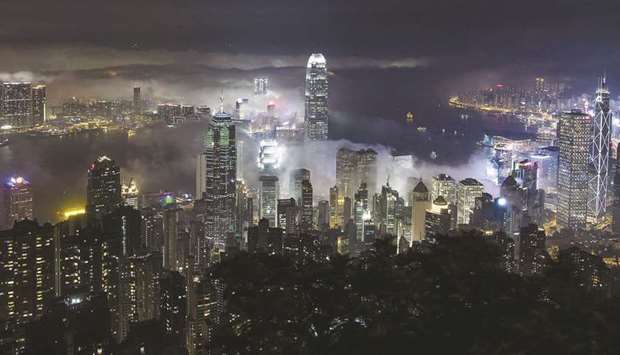 Commercial buildings standing illuminated and shrouded in clouds are seen from Victoria Peak at night in Hong Kong.