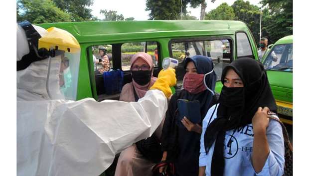 Passengers wearing face masks have temperature checked by a healthcare worker amid the spread of coronavirus disease (Covid-19) outbreak, on an intersection of the road in Bogor, West Java province, yesterday.