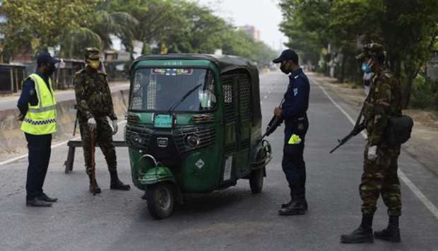 Policemen and army personnel stop a motorist at checkpoint along a road during a government imposed shutdown as a preventative measure against the Covid-19 coronavirus, in Narayanganj on the outskirts of Dhaka yesterday.