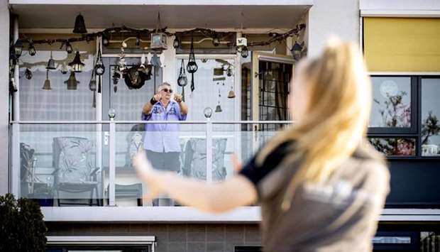 An elderly man takes part in an exercise class from his balcony in Kwintsheul, the Netherlands.